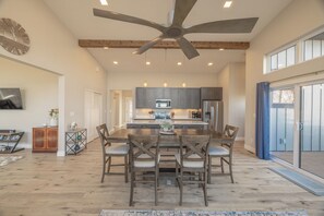 A spacious kitchen with a central island, wooden chairs, and a ceiling fan. - Altitude Adjustment by Innsbrook Vacations! (Innsbrook)