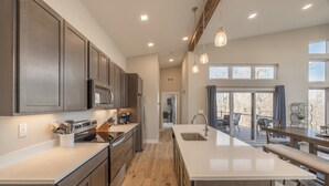 A modern kitchen with wooden cabinets, stainless steel appliances, and a large island. - Altitude Adjustment by Innsbrook Vacations! (Innsbrook)