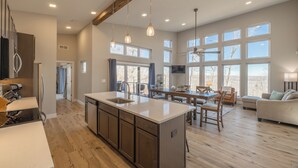 A spacious kitchen with a large island, wooden cabinets, and a dining area with a table and chairs. - Altitude Adjustment by Innsbrook Vacations! (Innsbrook)