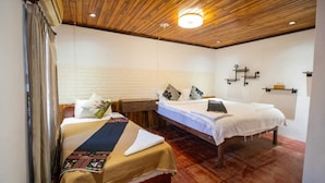 Un dormitorio con dos camas, techo de madera y pared de ladrillo blanco.