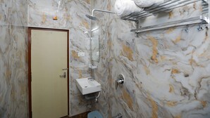 Une salle de bain avec un mur en marbre, une douche, un lavabo et un porte-serviettes.