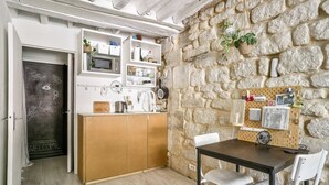Une cuisine compacte avec un mur en pierre, des placards en bois et une porte en ardoise.