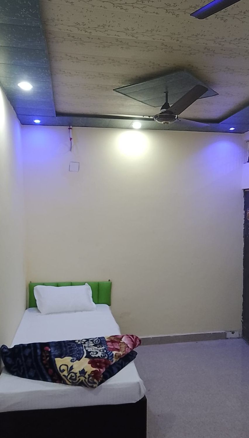 A bedroom with a bed, green headboard, and a ceiling fan.