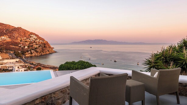 A terrace with wicker furniture overlooking a pool and a coastal view. - Villa Oleandri Mykonos (Mykonos)