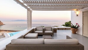 A covered outdoor seating area with wicker furniture and a view of the sea. - Villa Oleandri Mykonos (Mykonos)