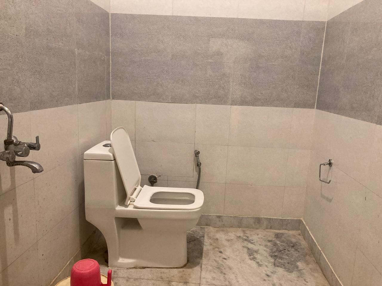 Un baño pequeño con azulejos, un inodoro, una ducha y un pasamanos.
