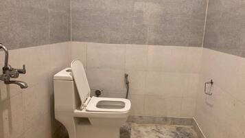 Un baño pequeño con azulejos, un inodoro, una ducha y un pasamanos.