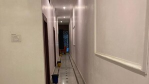 Un couloir doté d’un sol carrelé, de murs blancs et d’une porte au fond.