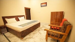Une chambre à coucher avec un grand lit, une chaise en bois, une table de chevet et une porte.