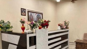 Un comptoir d’accueil avec un revêtement en marbre, de nombreux arrangements floraux et des tableaux encadrés accrochés au mur.