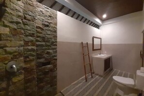 Une salle de bain avec un mur en pierre, une échelle en bois, un lavabo et des toilettes.