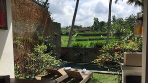 A pool area with lounge chairs, surrounded by lush greenery and a view of rice paddies. - Private One BD with Pool Overlooking to Rice Fields By Hidden Point Villa

 (Bali)