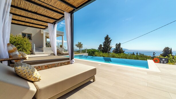Area piscina con vista sul mare, zona relax coperta e un galleggiante.