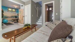 Un soggiorno moderno con un divano, una panca in legno e un pannello macramè a parete.