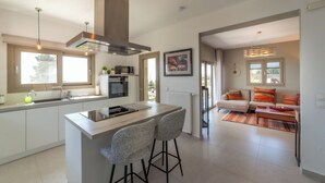 Una cucina moderna con isola centrale, sgabelli da bar e zona pranzo con divano e cuscini colorati.