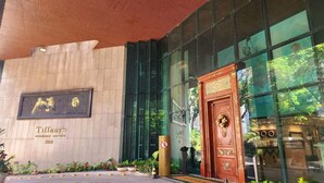 A modern building with a large glass entrance, a plaque with a family image, and a sign for Tiffany's residence service. - Renovated aparthotel located in the vibrant Ipanema district of Rio de Janeiro.  (Ipanema Rio de Janeiro)