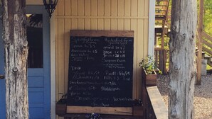 Une enseigne indiquant « Magasin de produits de la ferme » est placée au-dessus d’un tableau noir où sont affichés les prix de différents produits biologiques.