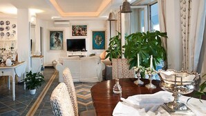 A modern living room with a wooden dining table, comfortable seating, and decorative items. - A Slice of Heaven by the sea - Beahost Rentals (Syracuse)