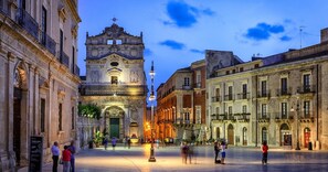 A historic square with a prominent church featuring a bell tower, surrounded by classical architecture.