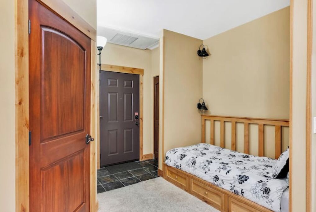 A bedroom with a wooden bed, a door, and a small bedside table.