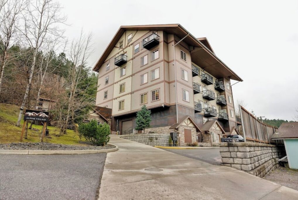 A multi-story building with balconies, a driveway, and a sign that reads "Alpine Village."