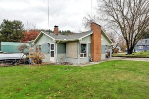 A single-story house with a green exterior and a brick chimney. - Miner's Home by Kannegaard with Pool Table and Bar

 (Kellogg)