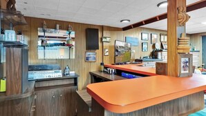 A restaurant with wooden paneling, a counter with orange top, and various kitchen appliances. - Miner's Home by Kannegaard with Pool Table and Bar

 (Kellogg)