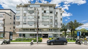 Un edificio de varios pisos con balcones, un letrero que dice 'Ed. Cozulem 1980' y vehículos estacionados.