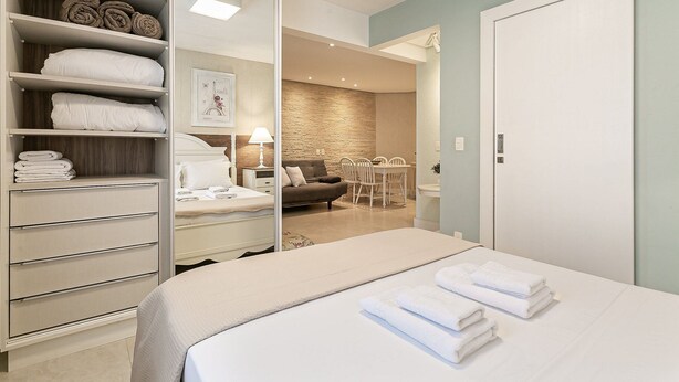 Habitación de hotel con cama, armario, zona de estar con sofá y sillones, y mesa de comedor.