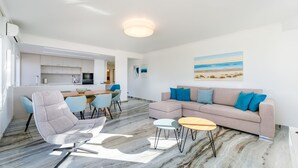 Una sala de estar moderna con sofá, sillas, una mesa de centro y un comedor con mesa y sillas.
