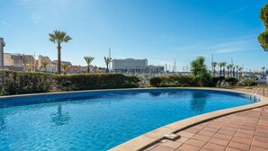 A swimming pool with a view of a marina and buildings in the background.