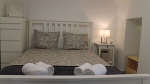 A neatly made bed with patterned pillows, a bedside lamp, and rolled towels. - Casa das Bonecas by LovelyStay (Évora Monte)