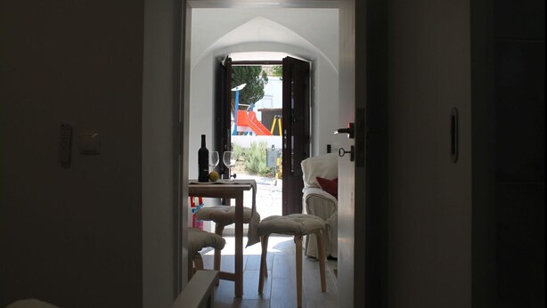A doorway leading to a room with a table, chairs, and a bottle of wine. - Casa das Bonecas by LovelyStay (Évora Monte)