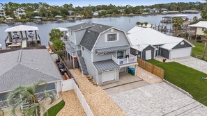 Une maison à deux étages avec un quai et un bateau, entourée d’eau et d’autres maisons.