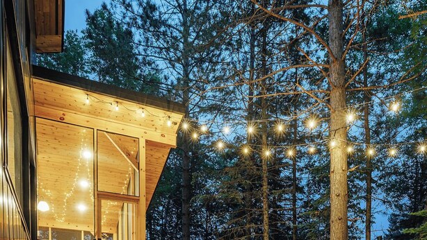 A wooden deck with outdoor seating, a staircase leading to an upper level, and a forested backdrop. - Cabin & Treehouse by Jay Cooke State Park / Duluth Trails (Esko)