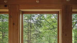 A wooden cabin room with a large window overlooking a forest. - Cabin & Treehouse by Jay Cooke State Park / Duluth Trails (Esko)