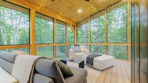 A spacious room with large windows, a ceiling fan, and a cozy seating area. - Cabin & Treehouse by Jay Cooke State Park / Duluth Trails (Esko)
