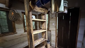 A rustic wooden cabin interior with a metal coffee pot, shelves, and a woven basket. - Unplug and hide from the world in this rustic South Pittsburg cabin (South Pittsburg)
