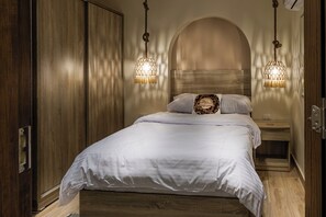 A bedroom with a wooden wardrobe, a bed with white bedding, and two hanging lamps. - Kush Hotel Grand Museum & Pyramids View (Giza)