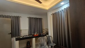 Una cucina moderna con un piano di lavoro nero, tende grigie e una ventola a soffitto.