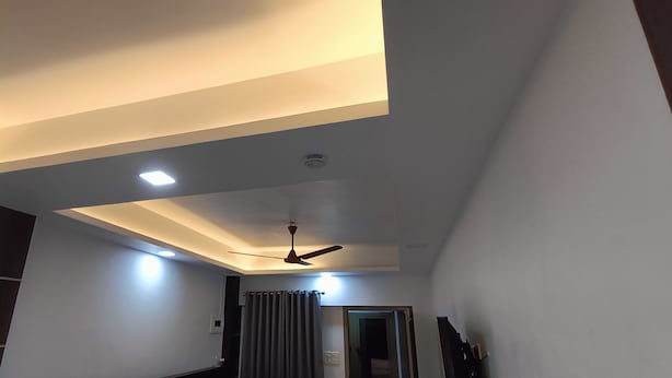 Una stanza con soffitto a falde, illuminazione incassata, ventilatore a soffitto e una porta che dà su un'altra stanza.