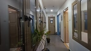 Un corridoio con porte, piante in vaso e un cartello che indica un'uscita.