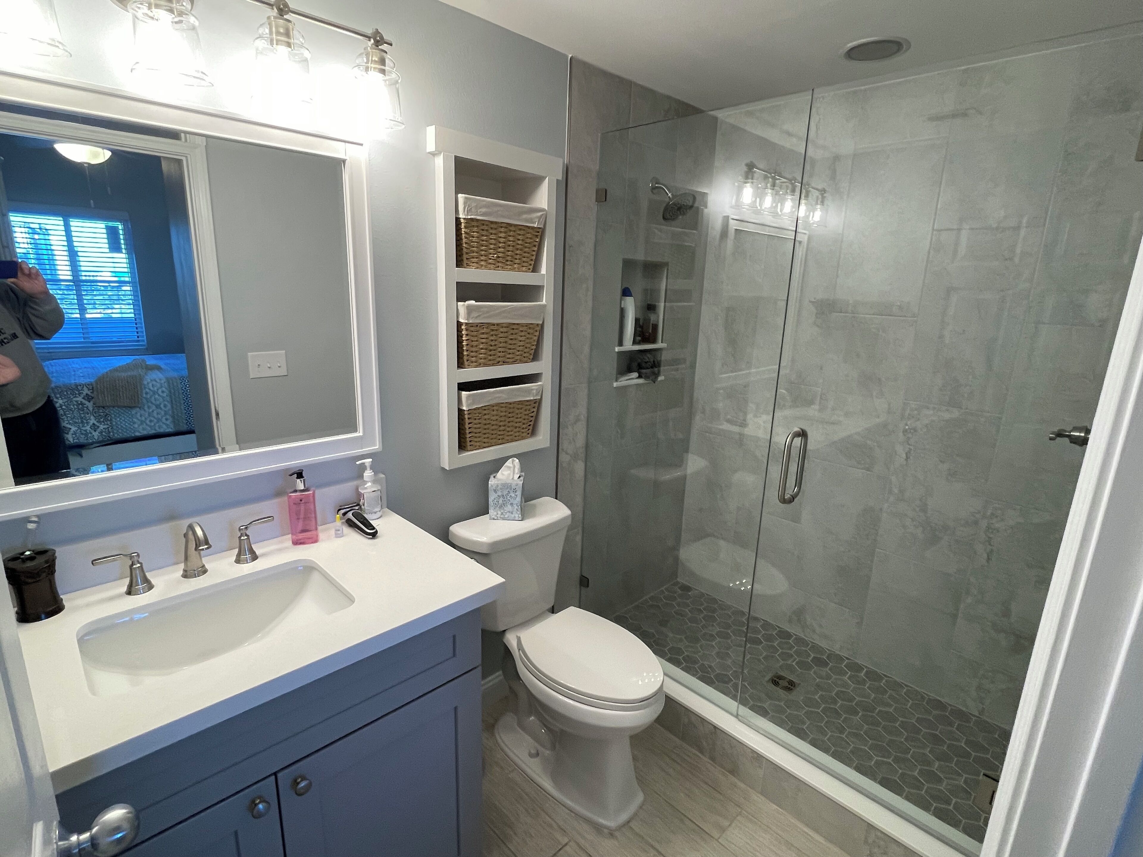 Un baño con lavamanos blanco, inodoro y cabina de ducha con paredes de vidrio.