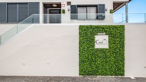 Un edificio moderno con una escalera que conduce a un balcón, una pared verde con un letrero y un cielo despejado.