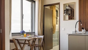 Una habitación con una mesa de comedor, sillas, un ventanal con cortinas, un lavabo y un espejo.