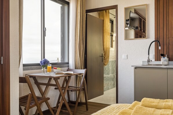 A room with a dining table, chairs, a window with curtains, a sink, and a mirror. - Cozy Apartment 3 by Homie (Porto Moniz)