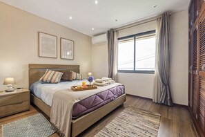 A hotel room with a bed, bedside tables, a window with curtains, and a wooden wardrobe.