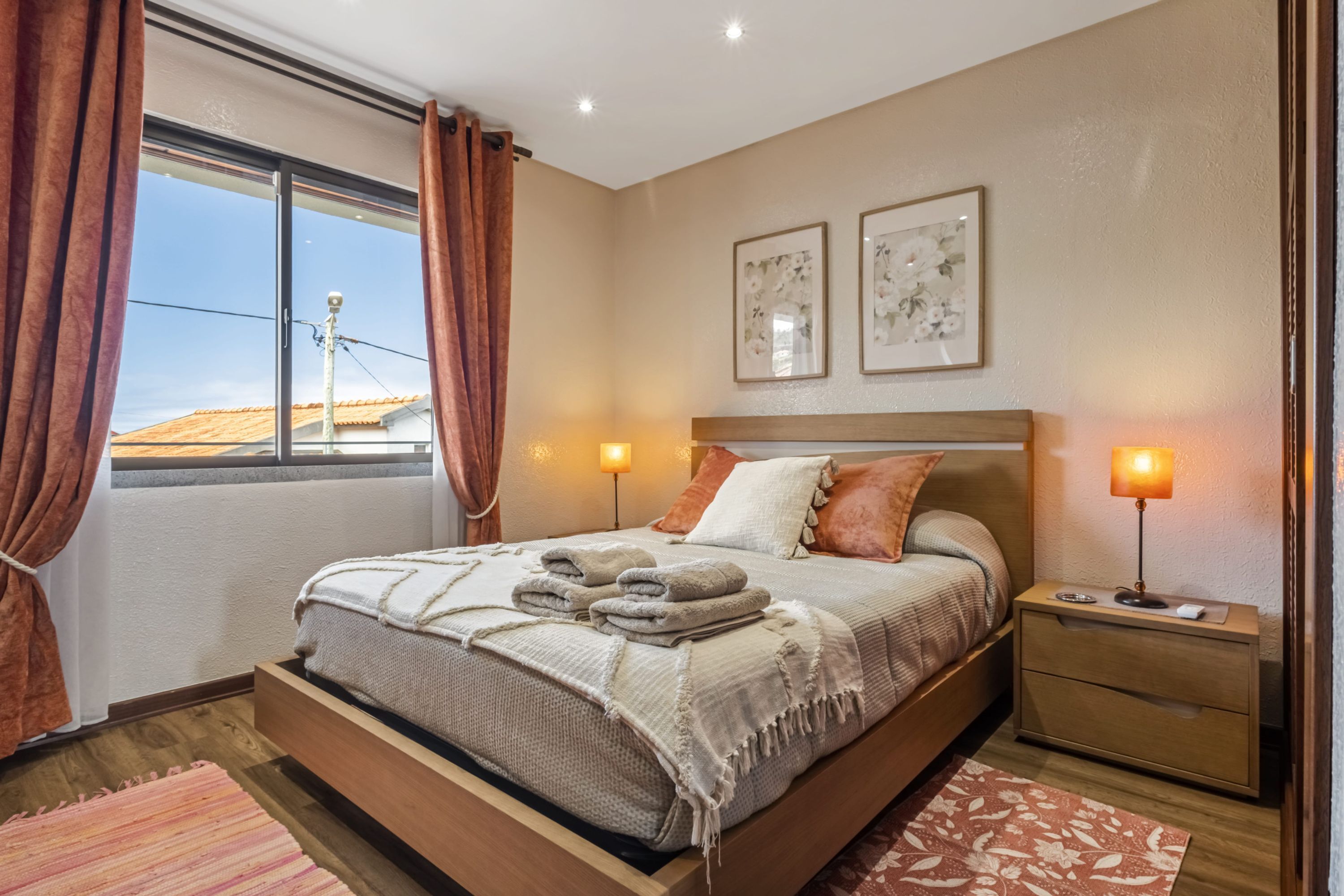 Een slaapkamer met een bed, nachtkastjes en een raam met gordijnen.