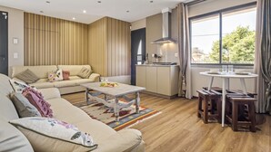 A modern living room with a sofa, coffee table, and a dining area with stools. - Cozy Apartment 1 by Homie (Porto Moniz)