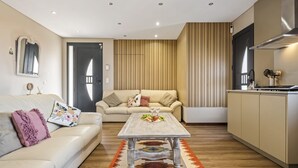 A modern living room with a sofa, a coffee table, and a kitchen area. - Cozy Apartment 1 by Homie (Porto Moniz)